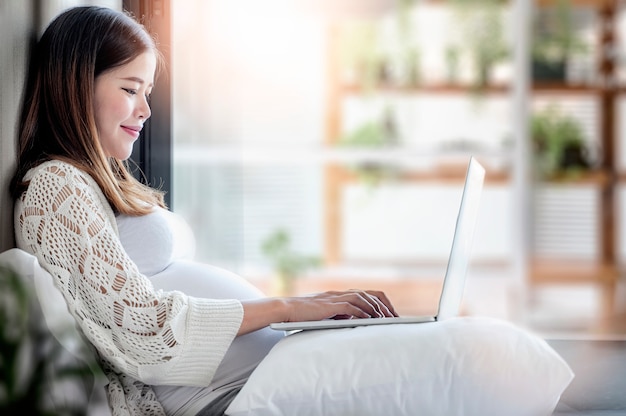 Zwangere vrouw die laptop thuis met behulp van.