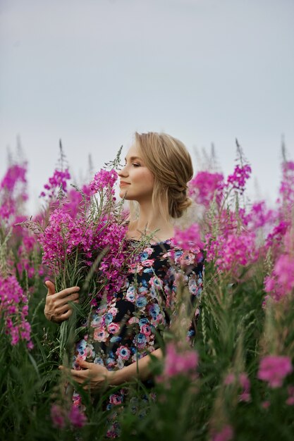 Zwangere vrouw die op gebied van bloemenwilgeroosje loopt