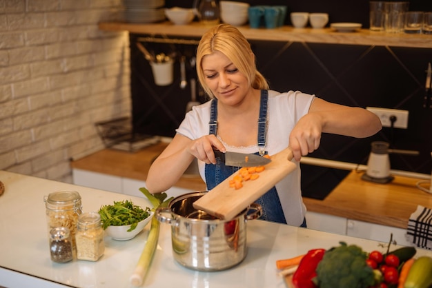 Zwangere vrouw die thuis in de keuken kookt.