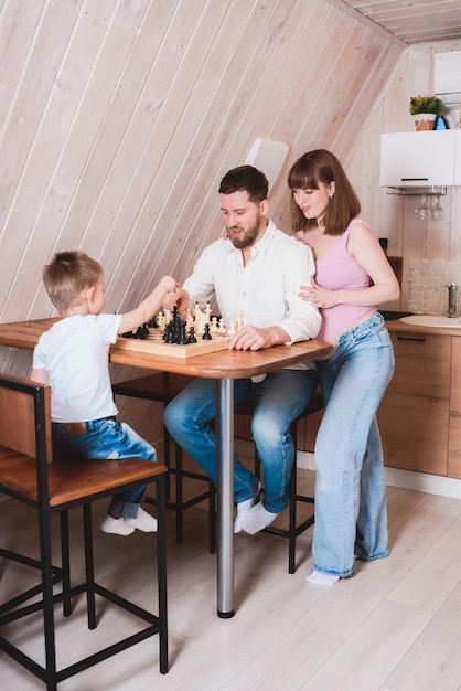 Zwangere vrouw die vader en zoon aan tafel ziet schaken