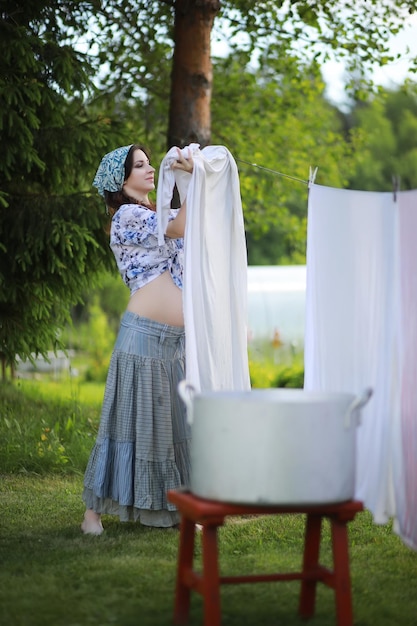 Zwangere vrouw die waskleren aan het touw hangt om te drogen