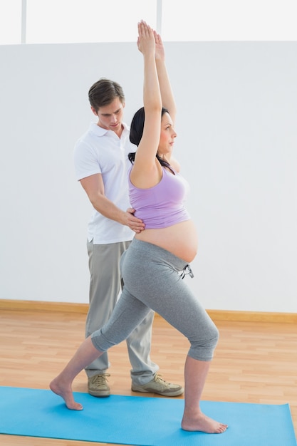 Zwangere vrouw die yoga met een persoonlijke trainer doet