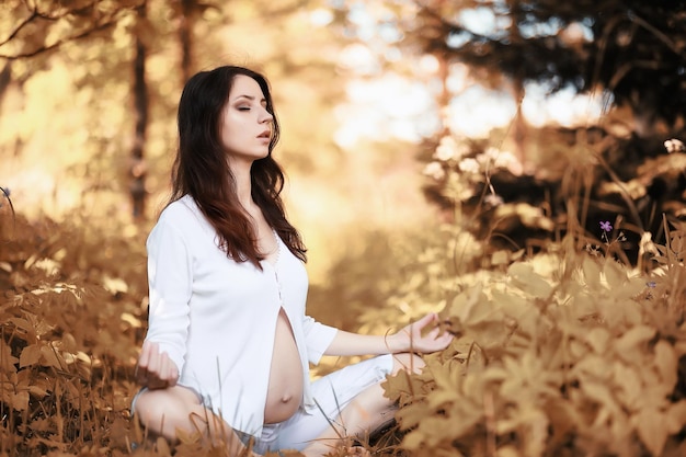 Zwangere vrouw die yogaoefening doet in de herfst