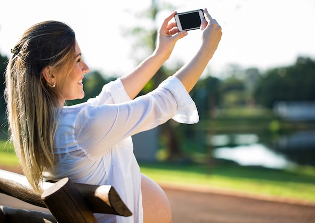 Zwangere vrouw die zelfportret maakt met behulp van smartphone