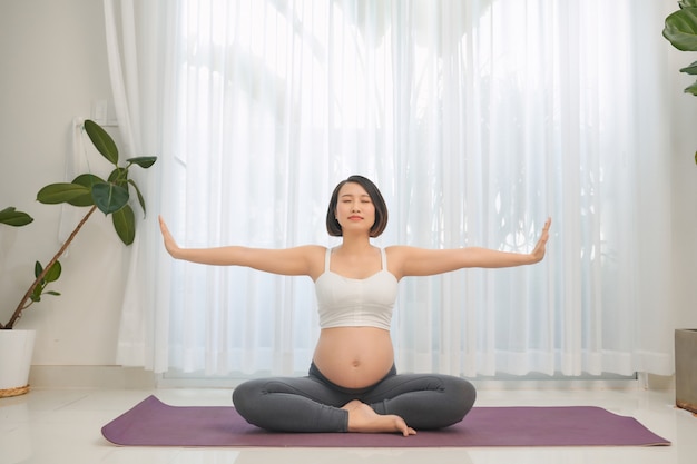 Zwangere vrouw doet yoga in de woonkamer