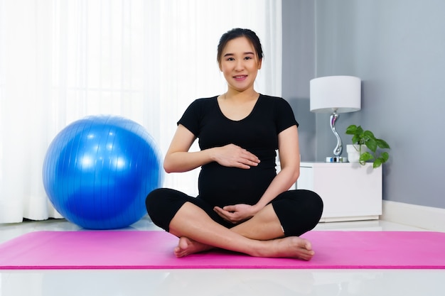 Zwangere vrouw doet yoga oefening in de huiskamer