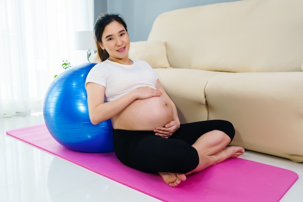 Zwangere vrouw doet yoga oefening op fitness bal in de huiskamer