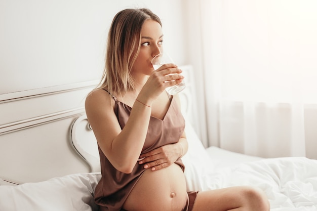 Zwangere vrouw drinkwater op bed