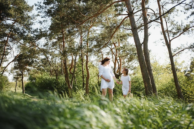 Zwangere vrouw en haar dochter in het park bij zonsondergang Een gelukkig gezin