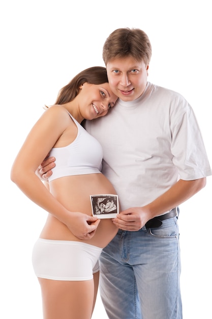 Zwangere vrouw en haar man houden haar buik vast en een foto van haar echografie
