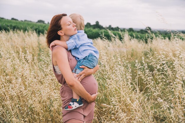 Foto zwangere vrouw en zoon in de natuur moeder wacht op een tweede baby