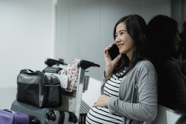 Zwangere vrouw gebruik mobiele telefoons om te bellen voor vertrek