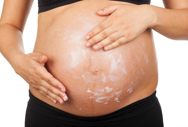 zwangere vrouw haar buik masseren met zalf tegen striae