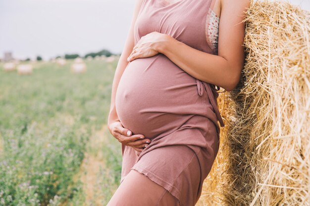 Zwangere vrouw houdt handen op buik op natuur achtergrond buiten