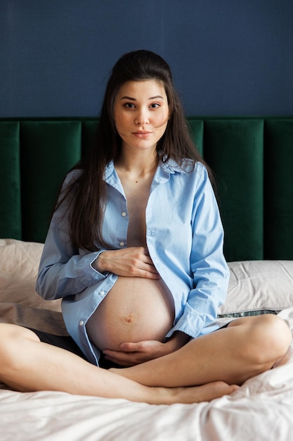 Zwangere vrouw in blauw shirt op bed thuis