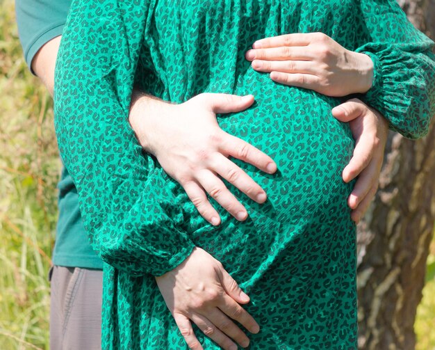 Zwangere vrouw in een groene jurk buiten op een zonnige dag