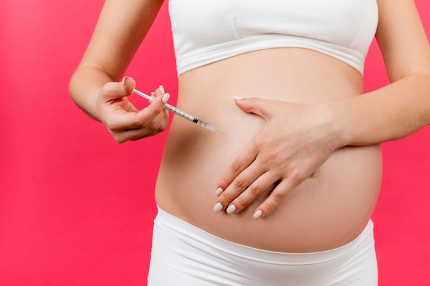 zwangere vrouw in geopende jeans streelt haar babybuil