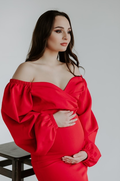 Zwangere vrouw in rode jurk op wit
