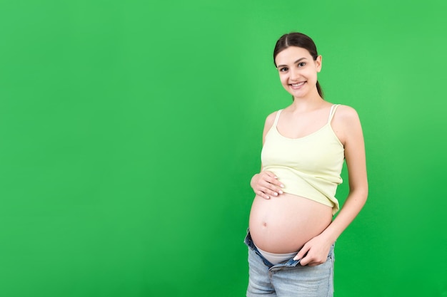 zwangere vrouw in unzipped spijkerbroek die haar baby buik toont op een kleurrijke achtergrond met kopieerruimte wachtend op een baby concept