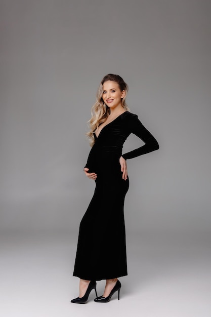 zwangere vrouw in zwarte jurk in studiomodel poseren in studio