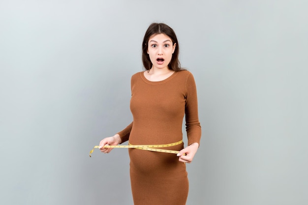 zwangere vrouw meet haar groeiende buik op gekleurde achtergrond inch meetband kopieer ruimte