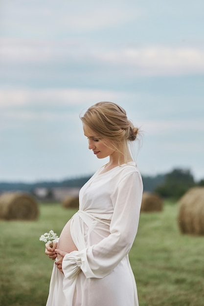 Zwangere vrouw met 9 maanden zwangerschap loopt in de zomer in het veld in het dorp, enkele dagen voor de geboorte van het kind