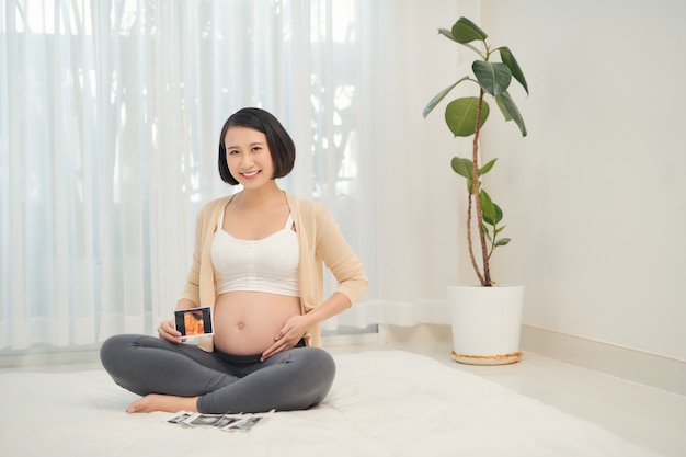 Zwangere vrouw met echografie foto in de buurt van buik