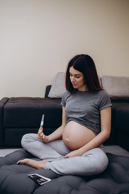 Zwangere vrouw met echografie foto zittend op bed