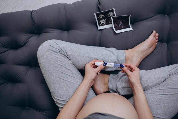 Zwangere vrouw met echografie foto zittend op bed