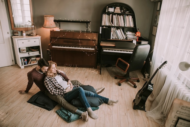 Zwangere vrouw met een man zittend op de vloer in de kamer