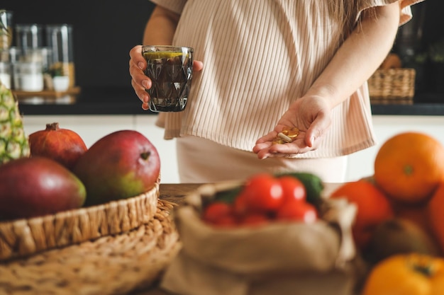 Zwangere vrouw met glas water en vitamines gezond zwangerschapsconcept