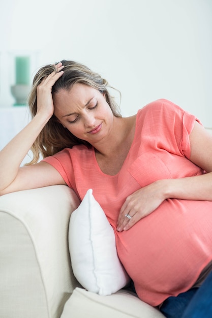 Zwangere vrouw met hoofdpijn op de bank