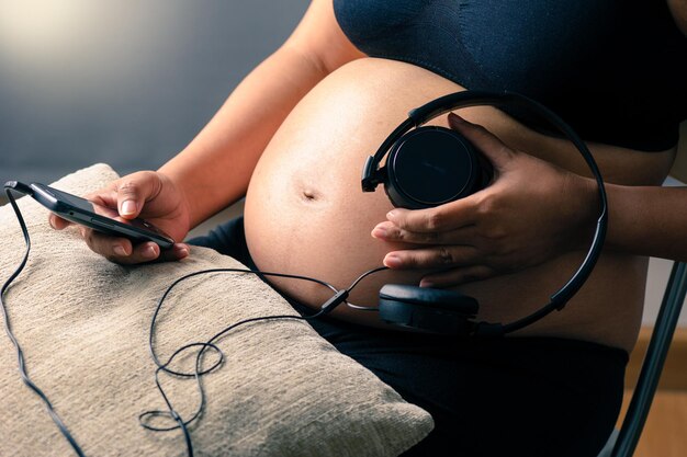 Zwangere vrouw met koptelefoon op haar buik