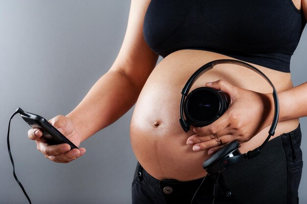 Zwangere vrouw met koptelefoon op haar buik