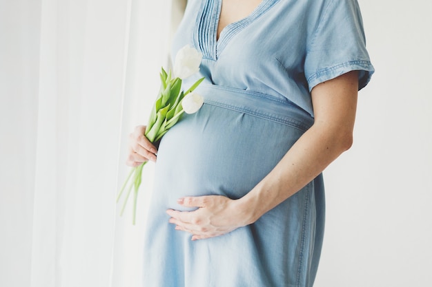 Zwangere vrouw met Lentebloemen. Levensstijl. Moederschap concept.