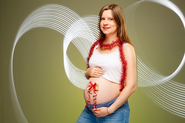 Zwangere vrouw met rode strik op haar buik verwacht baby op kerstavond