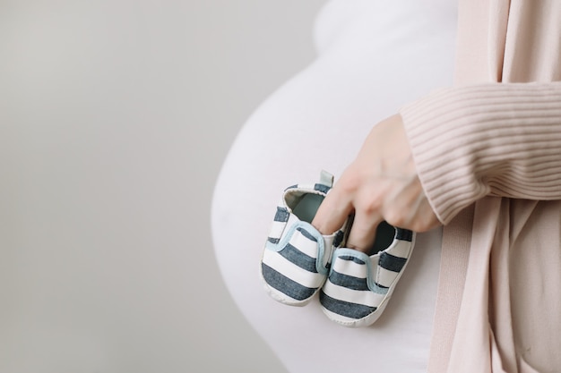 zwangere vrouw met schoenen voor de pasgeboren baby