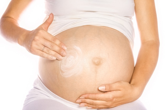 zwangere vrouw met zonnebrandcrème op de buik