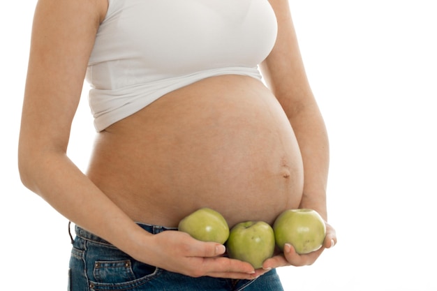 Zwangere vrouw poseren met groene appels in handen geïsoleerd op witte achtergrond