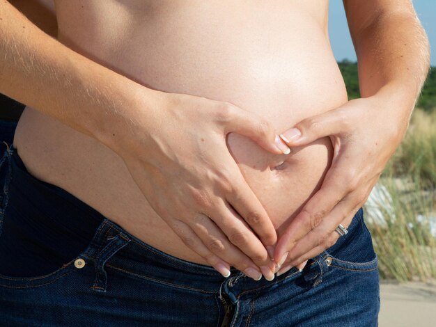 Zwangere vrouw staande buiten hand in hand op zwangerschapsbuik