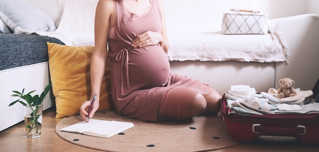 zwangere vrouw verpakkingstas voor kraamkliniek aanstaande moeder met koffer tijdens de zwangerschap