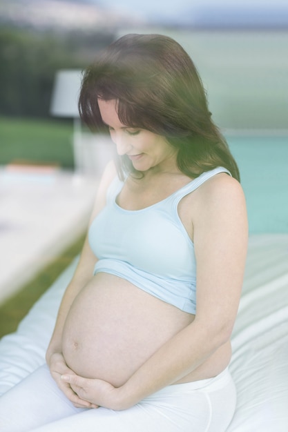 Zwangere vrouw wat betreft buik in haar slaapkamer