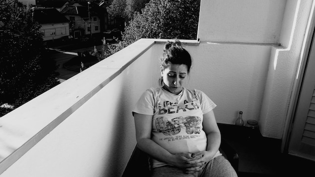 Foto zwangere vrouw zit op het balkon.
