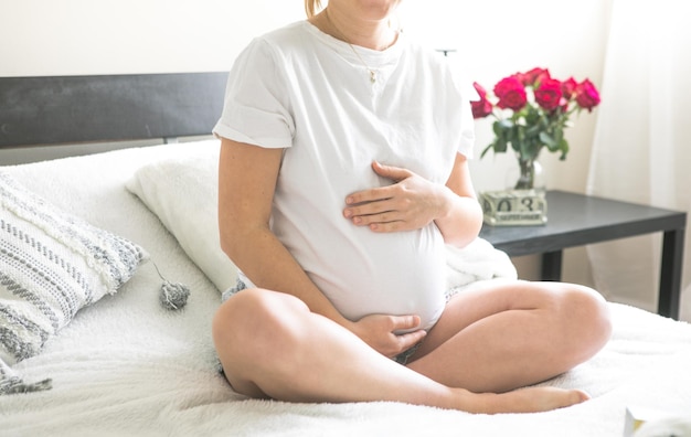 Zwangere vrouw zittend op een bed met het concept van zwangerschap, moederschap en prenatale zorg Mam met een nieuw leven