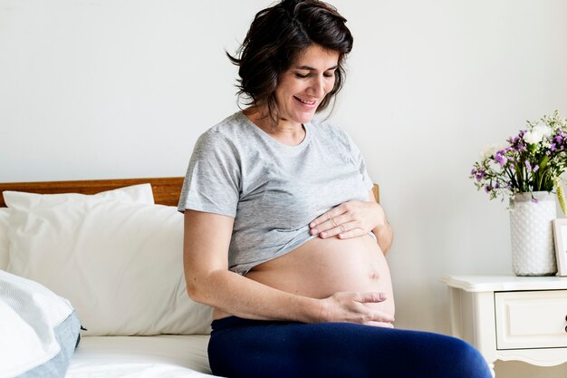 Zwangere vrouw zittend op het bed