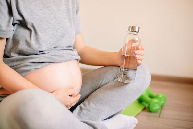 Zwangere vrouw zonder gezicht tijdens het sporten thuis