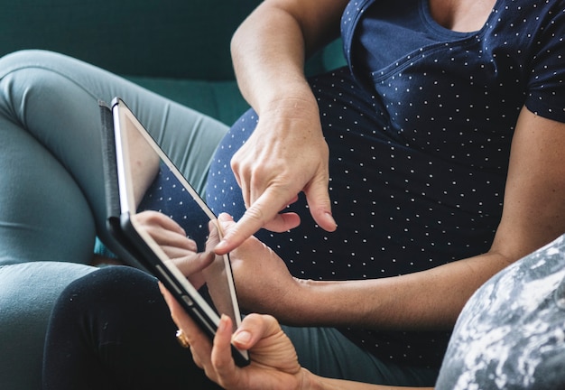 Zwangere vrouwen die digitale tablet samen gebruiken