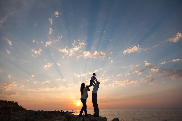 Zwangerschap en gelukkig gezin. De zwangere vrouw met haar man en kind hand in hand wandelen op de zee zonsondergang