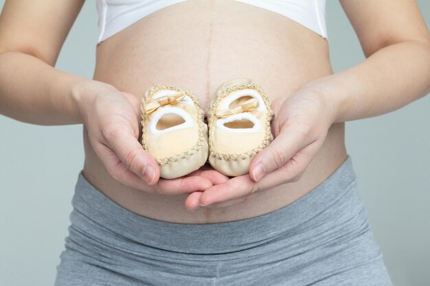 Zwangerschap Liefdevol concept Jonge zwangere en haar babyschoentjes