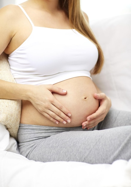 zwangerschap, moederschap, mensen en verwachtingsconcept - close-up van een gelukkige zwangere vrouw met blote buik thuis